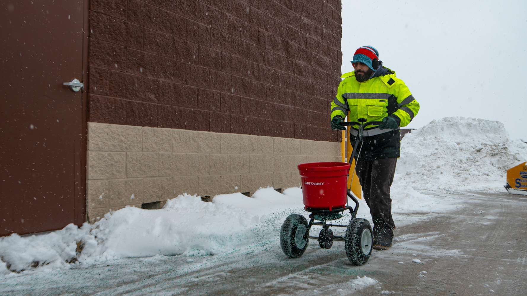 OUTLAND snow removal crew applying ice melt to a commercial sidewalk